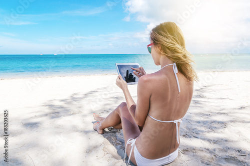 Happy young woman with a tablet in a tropical paradise resort. Communication during the holidays
