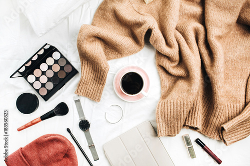 Female fashion look with stylish clothes and accessories. Lifestyle flat lay, top view composition with sweater, cosmetics and coffee.