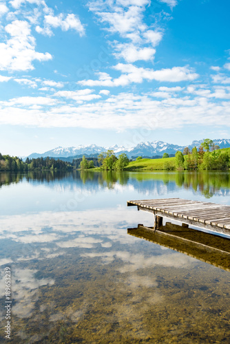 idylliczny-jezioro-z-drewnianym-molem-przy-stopa-alps-portret