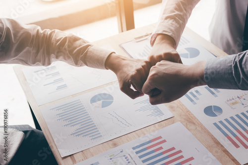 young-business-teamwork-giving-fist-bump-for-success-project-and-chart-report-on-desk