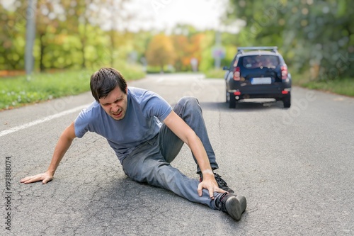 Hit and run concept. Injured man on road in front of a car. © vchalup