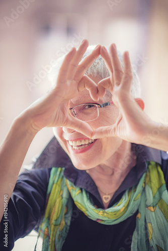 Cute senior old woman making a heart shape with her hands and fingers © Teodor Lazarev