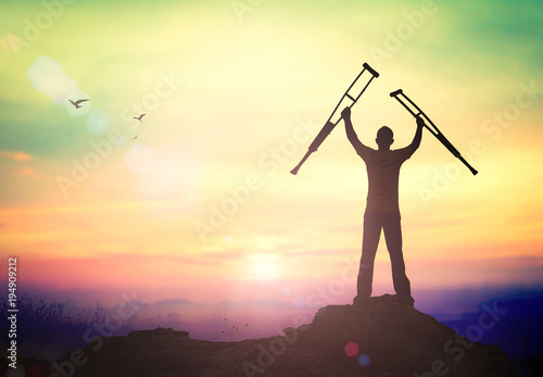 International Day of Persons with Disabilities (IDPD) concept: Silhouette a disabled man standing up and raising his crutches at mountain autumn sunset background © Choat