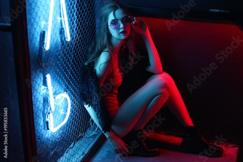 Girl, model in a black, fashionable fur coat and sunglasses in a nightclub. Fashion, style, beauty, night life.