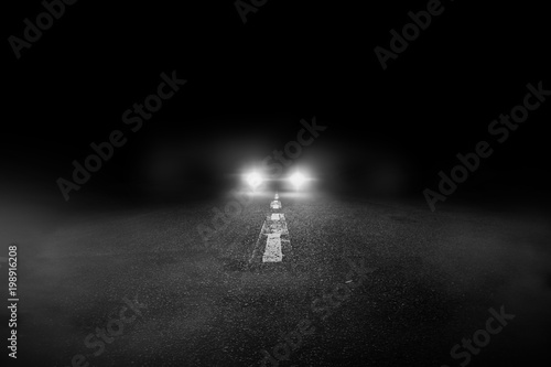 The lonely road at night with the car running.