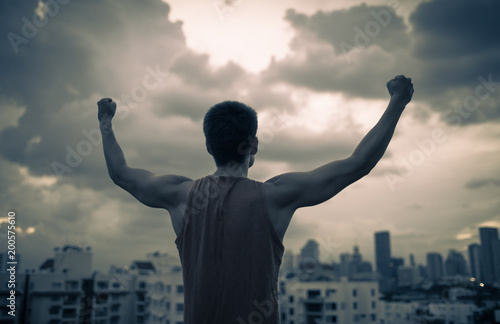 Strong man in the city with fist in the air. People overcoming fear, determination, and power concept.