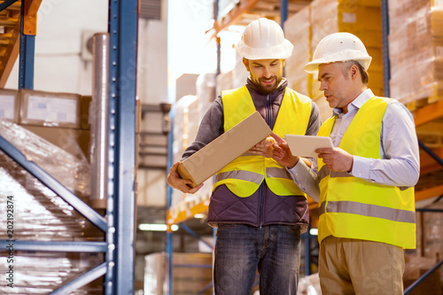 Professional control. Smart nice man standing together with his colleague while checking the box