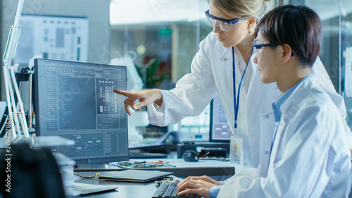 Two Prominent Computer Engineers Working with Programming Software on Personal Computer. In the Background Scientifically Advanced Research Center.