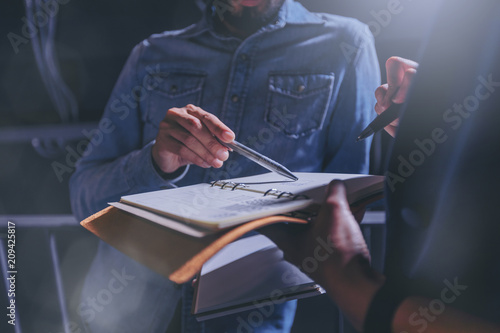 Man in jeans gives advice on work in a notebook with colleagues in office. Low key concept