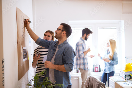 Young developers are brainstorming new algorithms how to make their software better optimized for users , while writing them down on a brownboard.