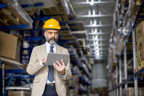 Middle-aged businessman with digital tablet in factory