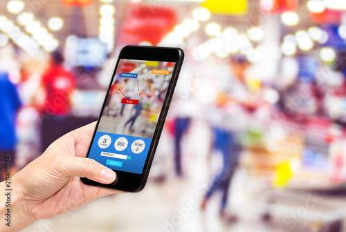 Hand hold mobile phone and using augmented reality ( AR ) app for see promotion sale in supermarket store,Digital lifestyle Technology concept. © weedezign