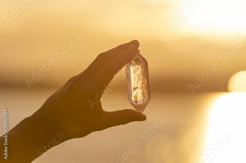 A hand holding up a beautiful quartz crystal outdoors in the sun © Hypnotik Photography