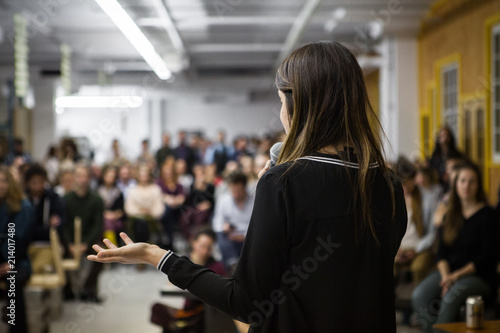 Woman gives a public speech in front of 200 people, in an industrial environment © Emmanuel