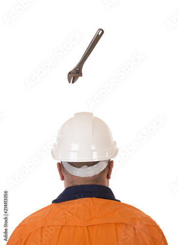 A tool falling from height towards a workers head which is protected by a safety helmet. © Tap10