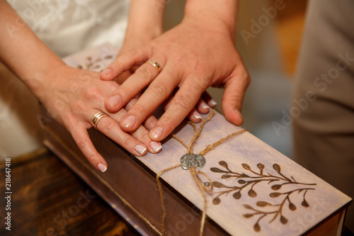 Wedding. Close-up view of young married couple, hands with wedding rings on decorated box. © Nick