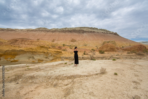 young woman in a black dress in the desert © serikbaib
