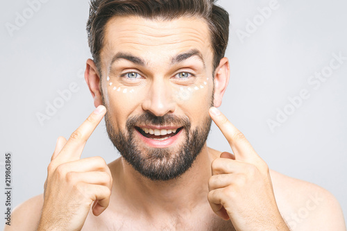 Skin Care Handsome Young Shirtless Man Lying Cream At His Face Skin Care Handsome Young Shirtless Man Lying Cream At His Face And Looking Himself