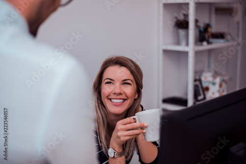 Charming beautiful business woman talking and discussing with her colleague in modern office. © bnenin