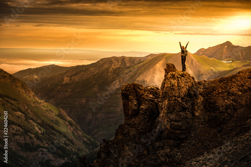 Young Woman Backpacker in Victory Pose with raised up arms on top of the Mountain Colorado USA
