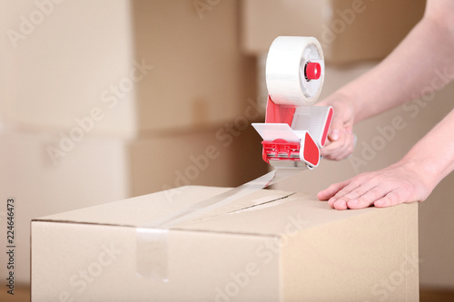 Female hands packaging cardboard box with dispenser