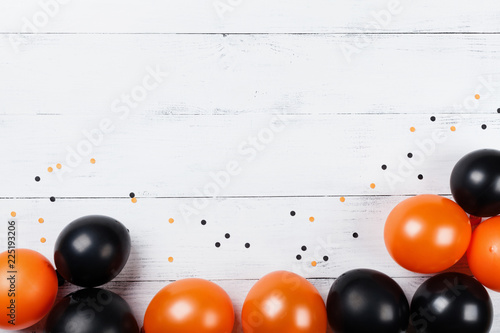 Black and orange balloons and confetti for Halloween card or invitation. Flat lay. © juliasudnitskaya