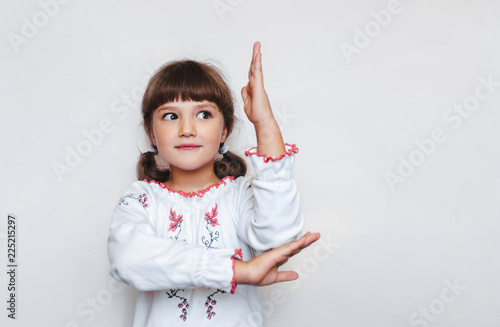 Beautiful little Ukrainian schoolgirl pulls her arm up. First-grade student. Ukrainian education. © shchus