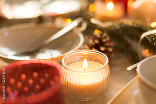christmas, holidays and decoration concept - candle burning on table served for festive dinner at home © Syda Productions