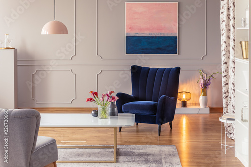 Real photo of a romantic living room interior with an armchair, painting, cozy light and flowers © Photographee.eu