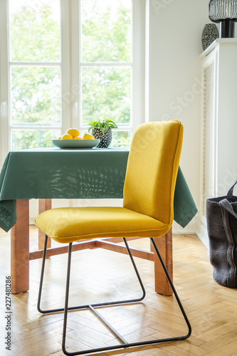 Fruit Bowl On A Wooden Table And Modern Chair With Bright Yellow Fruit Bowl On A Wooden Table And Modern Chair With Bright Yellow Upholstery In