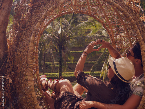 Couple sitting in love nest and holding heart shape in the middle of the jungle. Love concept. © Kitja