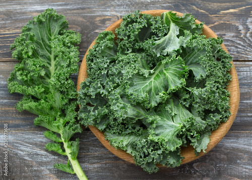 Fresh green curly kale leaves on a wooden table. selective focus. rustic style. healthy vegetarian food © olepeshkina