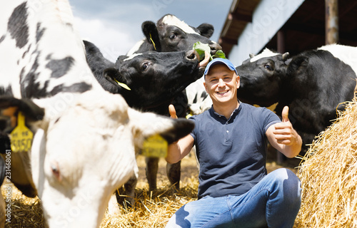 happy male farmer on cow farm around herd © jenoche