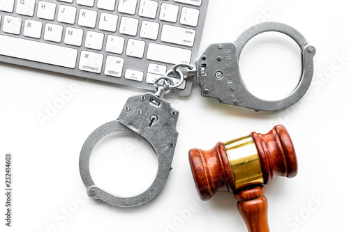 Arrest of a hacker for cyber fraud concept. Handcuff near keyboard and judge gavel on white background top view © 9dreamstudio