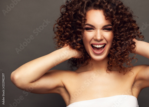 Fashion studio portrait of beautiful smiling woman with afro curls hairstyle. Fashion and beauty. © opolja
