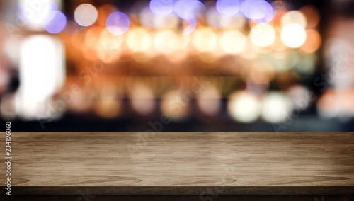 Wood table top with blur nightclub bar counter with bokeh light background,banner mock up for display of product or design content.