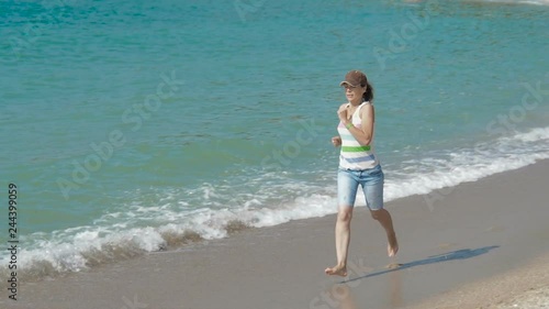 Woman running along the beach. © znaymeru