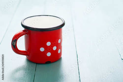 milk in dotted enamel mug, blue wood background