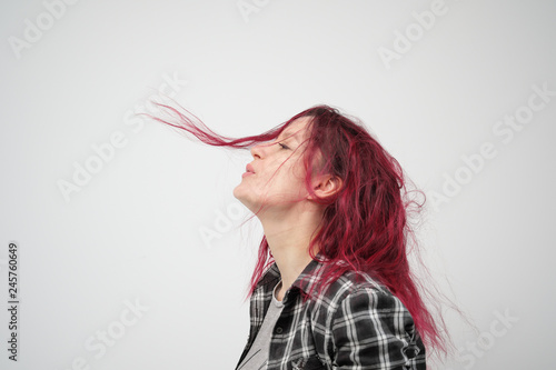 The girl in a plaid gray shirt on a white background with dyed red hair. © spaskov
