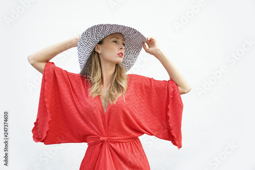 Attractive blonde posing in red dress and hat on white background © goodluz