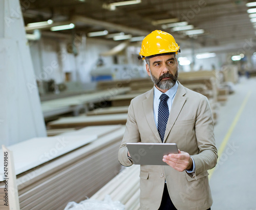 Middle-aged businessman with digital tablet in factory
