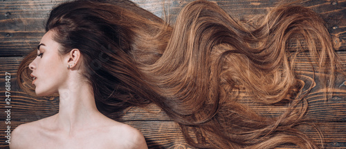 Woman with beautiful long hair on wooden background. Long hair. Trendy haircuts. Beauty hair Salon. © tverdohlib