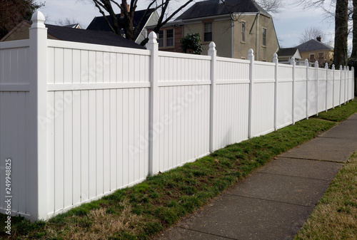 White vinyl fence in residential neighborhood. © Noel