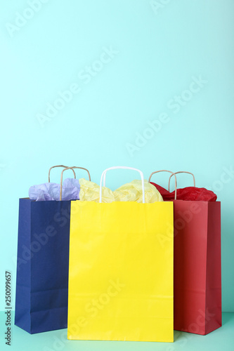 Colorful paper shopping bags on mint background