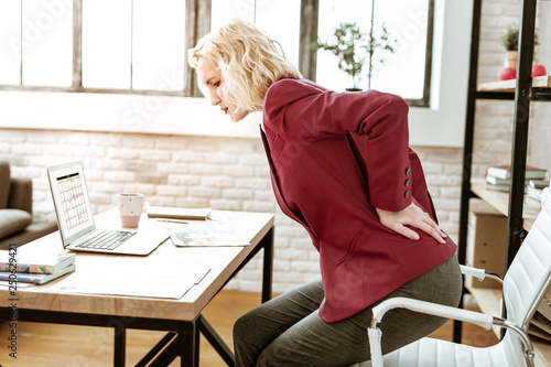 Stressed blonde woman having extreme backache at work © Viacheslav Iakobchuk