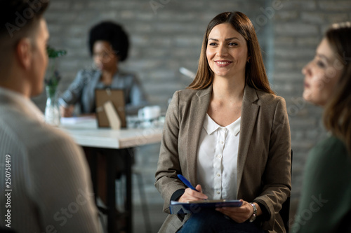 Happy financial advisor having a meeting with her clients in the office.