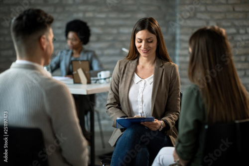 Happy financial advisor having an interview with a couple in the office.