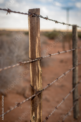 Rusty barb wire fence and old wood poles on Kalahari red sand farm © Anina Lonte
