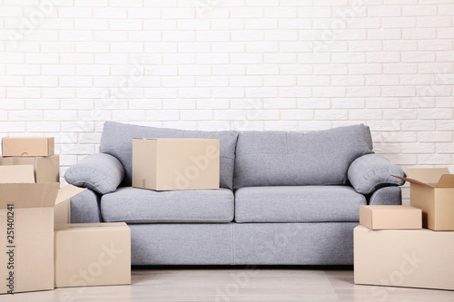 Cardboard boxes with grey sofa on brick wall background