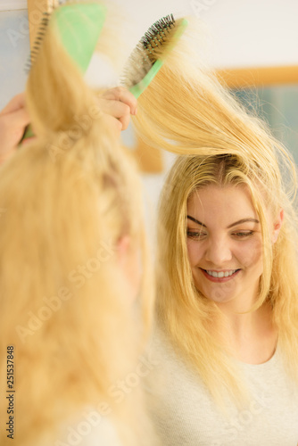 Woman brushing her blonde hair in bathroom © anetlanda